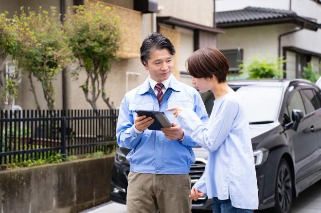 お車のそばで査定内容を説明するイメージ